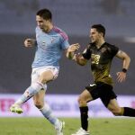 El defensa del Celta de Vigo Andreu Fontás (i) con el balón perseguido por el delantero del Elche Ferrán Corominas durante el partido