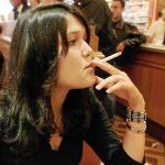 Una chica fuma un cigarrillo en un bar, mientras espera que el camarero le sirva