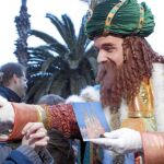 El Rey Gaspar recibe una carta de un niño con la imagen de la Sagrada Familia al comienzo de la cabalgata de Barcelona