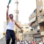Un copto cristiano, encaramado sobre un vehículo, durante los enfrentamientos con la Policía, ayer, en El Cairo