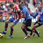 El mediocentro uruguayo del Sporting de Gijón Sebastián Eguren (i) protege el balón ante los jugadores del Atlético de Madrid el colombiano Luis Amaranto Perea (c) y el brasileño Elías Mendes durante el partido.