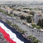 Los partidarios de Al Asad desplegaron ayer una enorme bandera siria en las calles de Damasco