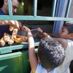 Varios niños hacen cola para recoger pan en una tienda cerca de Trípoli