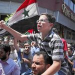 Un niño, a hombros de su padre, protesta en contra del régimen sirio en El Cairo, Egipto. La presión internacional va en aumento