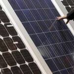 Un hombre toca la superficie de unas placas solares