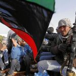 Un rebelde libio observa cómo la población celebra la recuperación de la ciudad de Ajdabiya tras vencer a las tropas gadafistas