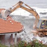 Una excavadora derriba una vivienda próxima a la playa