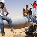Rebeldes libios se sientan sobre un misil en la base militar de Burkan, destruida ayer por los bombardeos de la OTAN