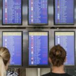 Varias personas observan un panel informativo del aeropuerto de Palma