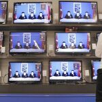 Una mujer ve en el escaparate de una tienda de televisiones el momento en el que los etarras leen el comunicado