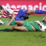 El delantero argentino del Sporting de Gijón Oscar Trejo (encima) cae en presencia del centrocampista griego del Racing de Santander Alexandros Tziolis
