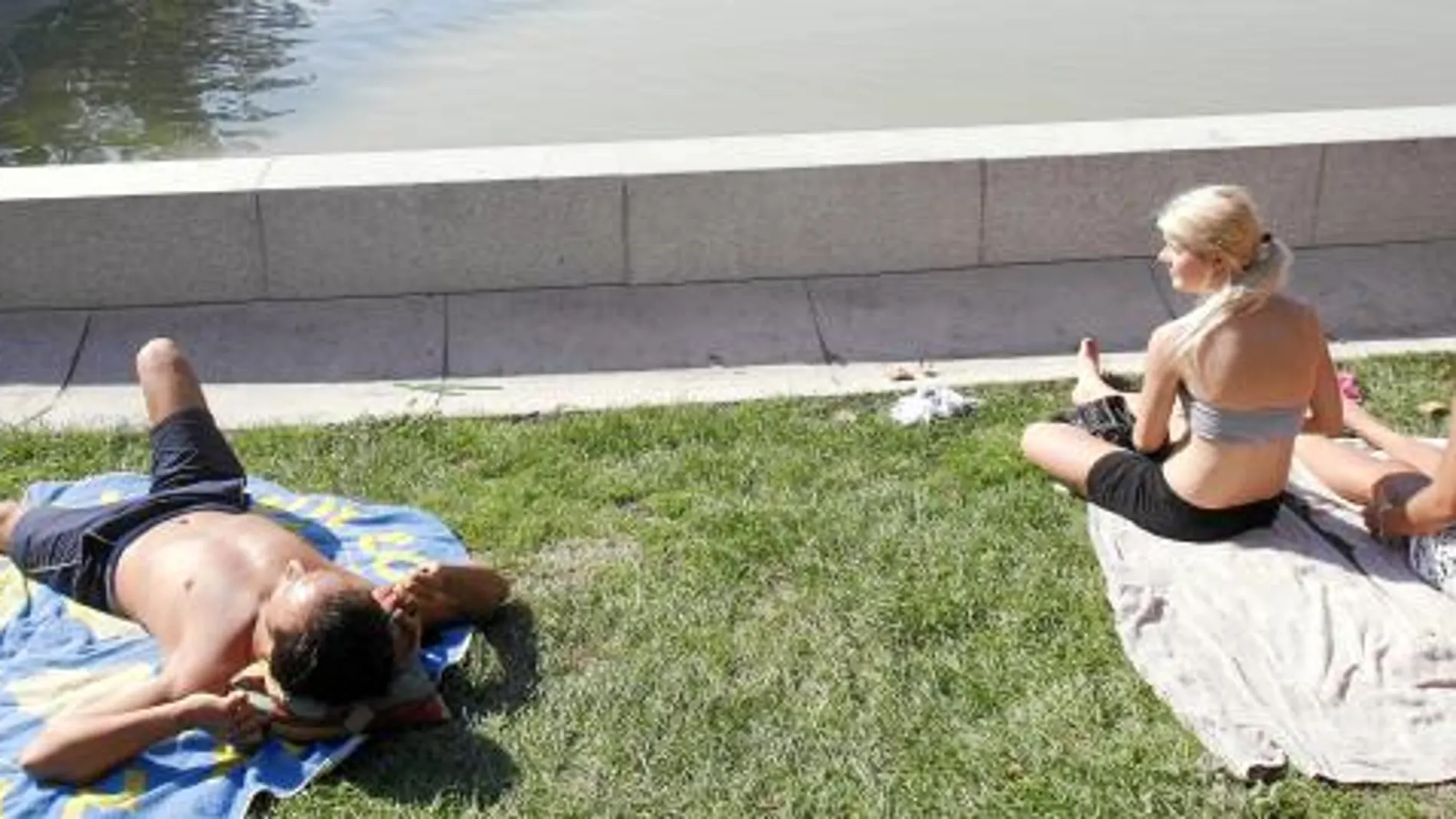 Tres jóvenes tomando el sol, ayer, en el madrileño parque de El Retiro