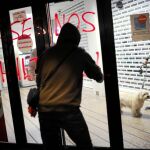 Un hombre encapuchado hace una pintada de protesta en una sucursal bancaria