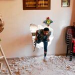 Un rebelde sirio entra a un edificio por un agujero en la pared para protegerse de los bombardeos en Alepo