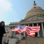 Un hombre con una bandera de los Estados Unidos delante del Capitolio en Washington