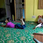 Un niño ve la televisión mientras su hermana juega con un arma de juguete en Srinagar