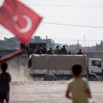 Niños ondean la bandera turca mientras saludan a los soldados sirios apoyados por Turquía que se dirigen al norte de Siria. Efe