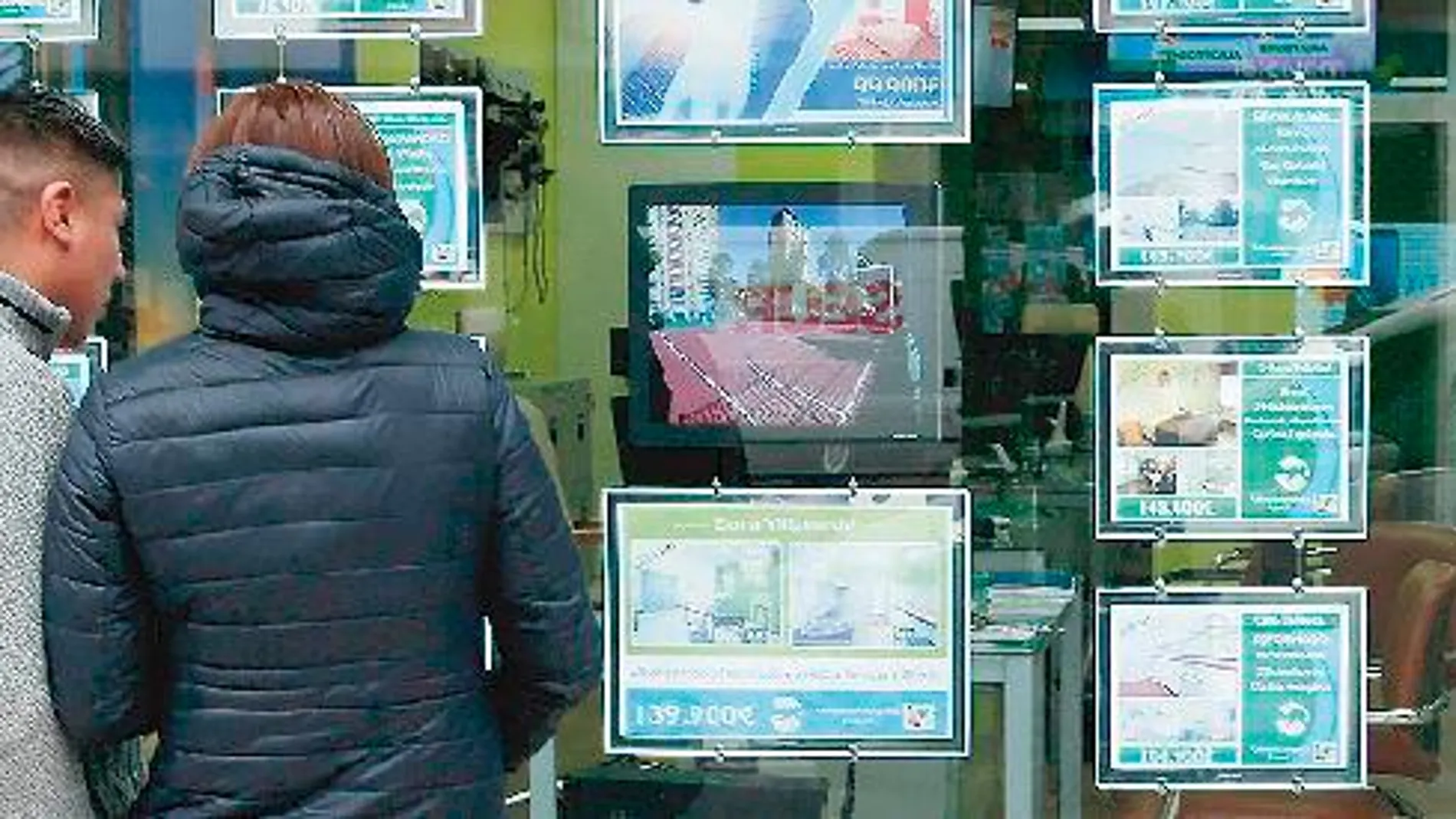 Ciudadanos observan un panel con distintas ofertas de vivienda en propiedad