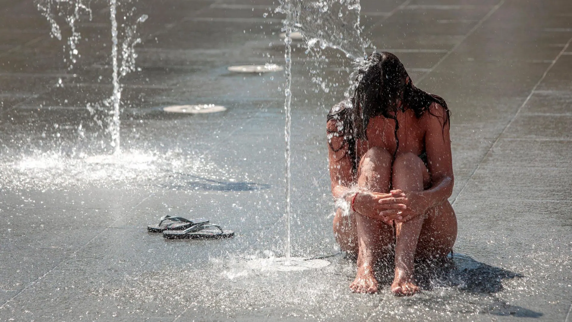 Una persona se refresca en una fuente del Parque Central de Valencia.