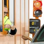 Un trabajador de una cabina de peaje cobra a un usuario