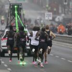 KIpchoge, rodeado de sus liebres. Por delante, el coche que les marcaba el camino