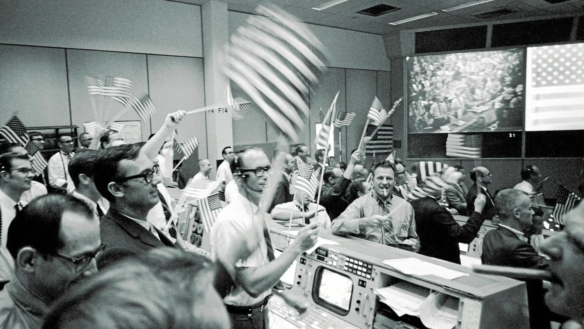 Los ingenieros de seguimiento de vuelo celebran el aterrizaje de la nave en el centro de control de Houston