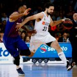 El jugador del Real Madrid Sergio Llull (d) trata de escapar de Adam Hanga (i), del Barcelona Lassa, durante el tercer partido de la final de la Liga Endesa