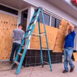 Empleados de una tienda de piezas de coche cubren un local con tablones de madera por la llegada de Dorian
