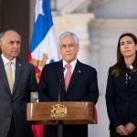 Fotografía de archivo del 30 de octubre de 2019 cedida por la Presidencia de Chile, que muestra al presidente Sebastián Piñera (c), acompañado de la ministra de Medio Ambiente, Carolina Schmidt (d), y el ministro de Exteriores, Teodoro Ribera (i), mientras anuncia la suspensión de las cumbres del APEC y la COP25, las dos reuniones multilaterales más importantes que se iban a llevar a cabo antes de fin de año, en el Palacio de La Moneda, en Santiago (Chile)