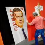 Imagen de un operario colocando un cartel de Pedro Sánchez en Pamplona