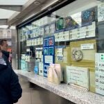 Dos personas compran un décimo de Lotería de Navidad en una Administración en la plaza de Puerta del Sol, en Madrid (España)