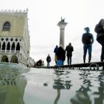 Gente caminando sobre las plataformas en Venecia, ayer, después de una nueva crecida del agua / Ap