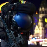 Un policía con una ametralladora hace guardia frente a la iglesia conmemorativa Kaiser-Wilhelm-Gedaechtniskirche con el mercado navideño en la plaza Breitscheidplatz