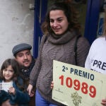 Adela (d), la dueña de la administración de lotería 'Los Buhítos de la 31' situada en la calle Felix Boix, 4 de Madrid, junto a una familia de agraciados con el segundo premio, el número 10989, parte del cual, se ha distribuído en su local, en Madrid (España), a 22 de diciembre de 2019