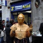 Una persona disfrazada del robot de la Guerra de las Galaxias C-3PO celebra en la administración de lotería 150 en la calle Arenal de Madrid donde se ha vendido una serie del tercer premio del Sorteo Extraordinario de Navidad, el número 00750.