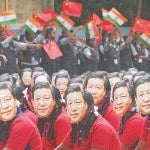 Varios estudiantes con una careta del presidente de China, Xi Jinping, en un congreso en India