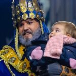 El Rey Melchor junto a una pequeña en la cabalgata de 2019