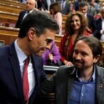 Pedro Sánchez, quien logró este martes la confianza del Congreso para un nuevo mandato como presidente del Gobierno, al lograr una estrecha mayoría de 167 votos a favor, 165 en contra y 18 abstenciones, es felicitado por el líder de Unidas Podemos, Pablo Iglesias (d). EFE/Juan Carlos Hidalgo