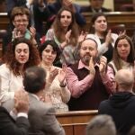 La diputada de Unidas Podemos, Aina Vidal (con chaqueta blanca), se emociona al recibir el aplauso de su bancada junto la socialista, tras el agradecimiento que le ha expresado Pablo Iglesias por haber asistido a la votación a pesar de estar enferma/Ep