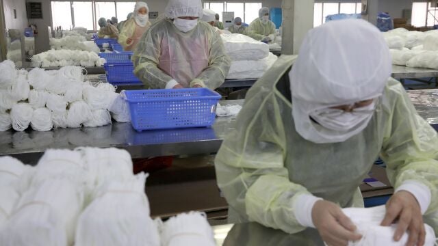 Varias personas trabajan en una fábrica de mascarillas este lunes en Nantong (China).