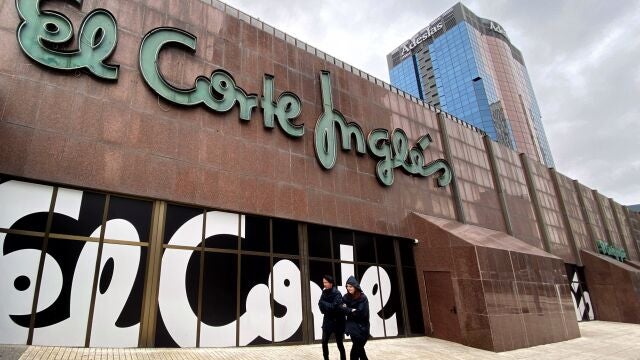 Dos personas pasan junto a unas letras de El Corte Inglés en el edificio de estos almacenes de Nuevos Ministerios, en Madrid
