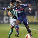 El jugador del Olympique Lyon, Henri Bedimo, controla el balón junto al defensa Juanfran Moreno, jugador del Real Betis en ese momento