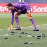 El guardameta del Osasuna Sergio Herrera retira las carteras lanzadas por los aficionados al terreno de juego en protesta al club, durante el partido correspondiente a la jornada 23 de LaLiga Santander, que se disputa este domingo en el estadio El Sadar de Pamplona. EFE/Villar López