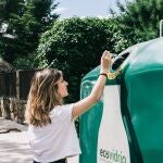 Una mujer deposita envases de vidrio en el contenedor