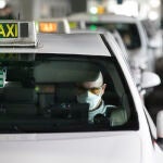 Un taxista con mascarilla espera en el aeropuerto de Madrid
