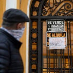 Un hombre con mascarilla pasa frente a unos carteles en un inmueble