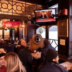 Um grupo de londinenses en un pub mientras en el televisor el premier britanico anuncia las nuevas medidas de gobierno.