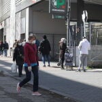 Decenas de personas protegidas con mascarillas hacen cola para poder entrar en un supermercado Mercadona