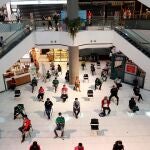 Repartidores de comida a domicilio esperan nuevos pedidos de clientes en un centro comercial, cerrado al público por el coronavirus, donde se les ha habilitado asientos para mantener la distancia