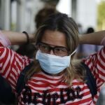 ES5001.SAN SALVADOR (EL SALVADOR), 27/03/2020- Una ciudadana española se coloca una mascarilla antes de ingresar al aeropuerto hoy viernes, después de ser trasladados desde la sede de la Embajada de España en El Salvador, para abordar un vuelo y regresar a su país de origen, en San Salvador. Un grupo de 47 españoles salió este viernes de El Salvador hacia su país tras quedarse en la nación centroamericana por las medidas impuestas para evitar la propagación de la pandemia del coronavirus. EFE/Rodrigo Sura